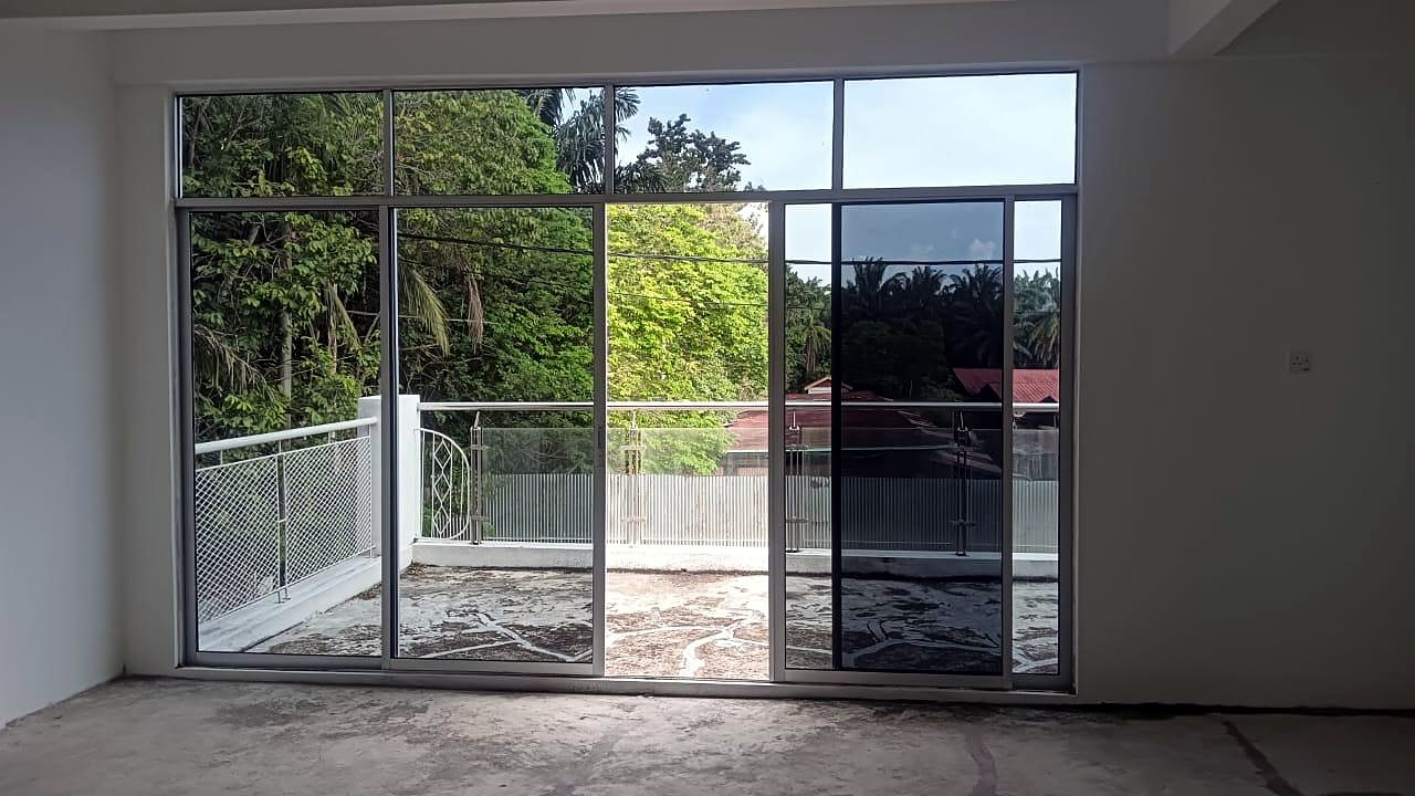 Ruang tamu terbuka dengan pintu kaca gelangsar setinggi dinding menghadap balkoni.